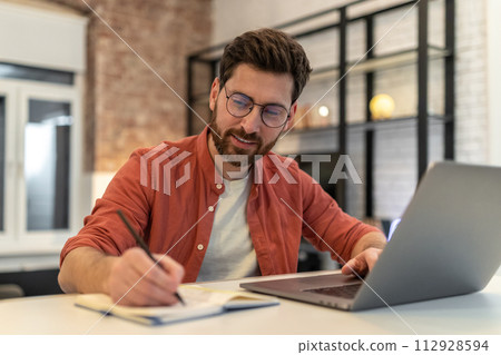 Man in eyeglasses working and looking involved Man in eyeglasses working and looking involved 112928594