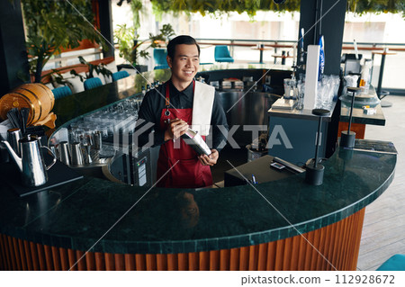 Smiling bartender making cocktail at bar counter Smiling bartender making cocktail at bar counter 112928672