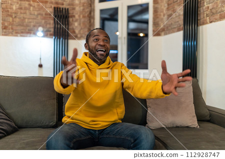 Dark-skinned man in yellow hoodie looking excited Dark-skinned man in yellow hoodie looking excited 112928747