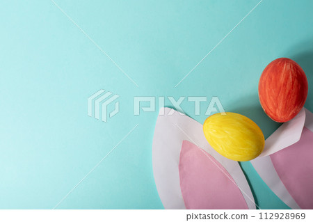 Colorful Easter eggs and pink rabbit ears on blue background, space for text 112928969