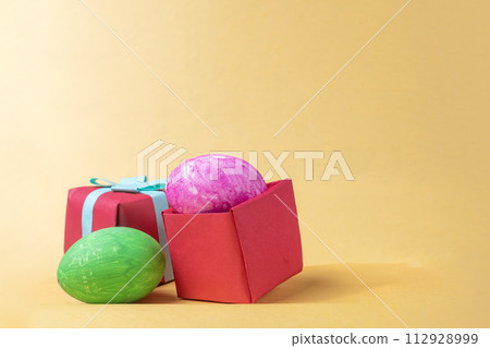 Colorful easter eggs in red gift box on yellow background. Colorful easter eggs in red gift box on yellow background. 112928999
