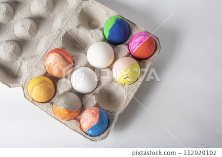 Colorful painted Easter eggs on a cardboard tray on a white background 112929102