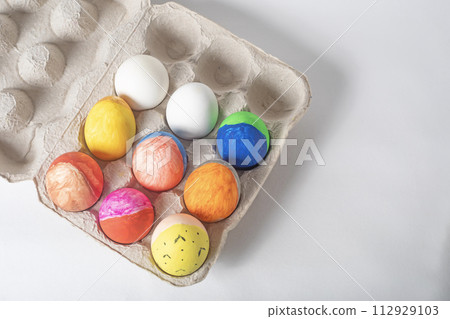 Colorful easter eggs in a cardboard box on a white background. Colorful easter eggs in a cardboard box on a white background. 112929103