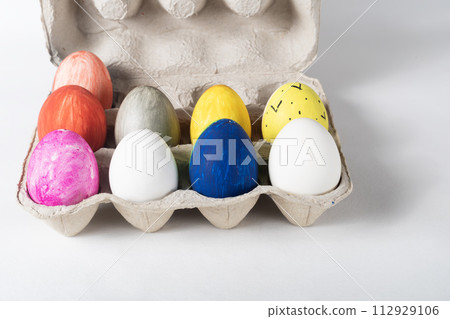 Colorful painted Easter eggs on a cardboard tray on a white background. Easter concept. Colorful painted Easter eggs on a cardboard tray on a white background. Easter concept. 112929106
