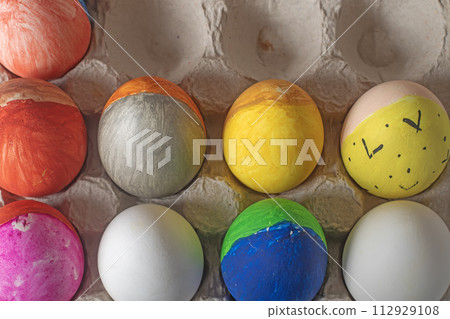 Easter eggs painted in bright colors in a cardboard box. Happy Easter concept. Easter eggs painted in bright colors in a cardboard box. Happy Easter concept. 112929108