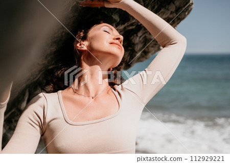 Woman travel sea. Sporty happy middle aged posing on a beach near the sea on background of volcanic rocks, like in Iceland, sharing travel adventure journey Woman travel sea. Sporty happy middle aged posing on a beach near the sea on background of volcanic rocks, like in Iceland, sharing travel adventure journey 112929221