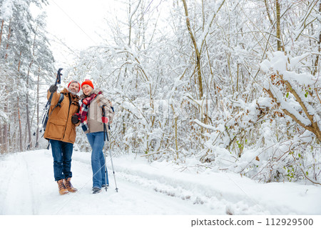 Two people with backpacks and scandinavian sticks in a forest Two people with backpacks and scandinavian sticks in a forest 112929500
