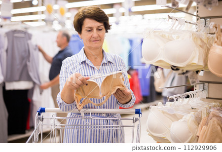 Mature woman choosing bra in supermarket Mature woman choosing bra in supermarket 112929906