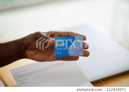 Hand of Black man showing new credit card he got in bank Hand of Black man showing new credit card he got in bank 112929971