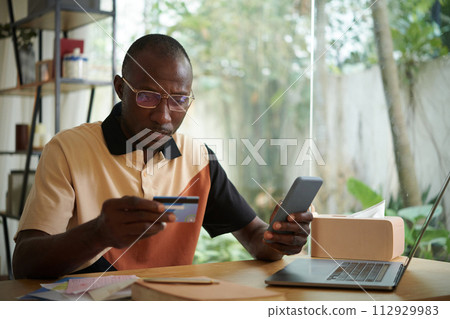 Black man paying for phone service with credit card Black man paying for phone service with credit card 112929983