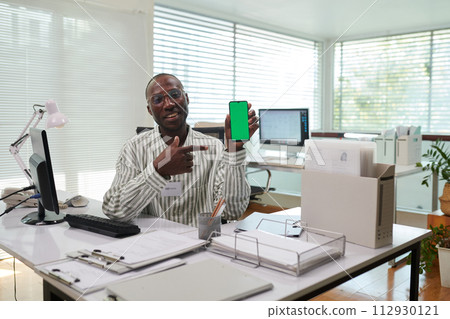 Portrait of positive Black office manager showing banking application on smartphone, green screen Portrait of positive Black office manager showing banking application on smartphone, green screen 112930121