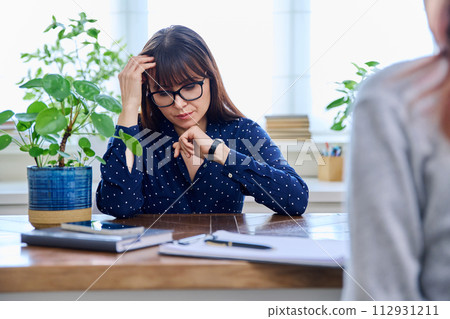 Mature sad woman in therapy session with mental professional Mature sad woman in therapy session with mental professional 112931211