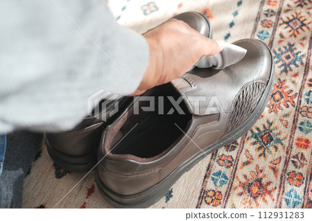 man wipes his leather shoes with a wet cloth man wipes his leather shoes with a wet cloth 112931283