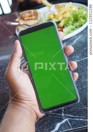 young man hand using smart phone with green screen at cafe young man hand using smart phone with green screen at cafe 112931286