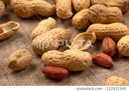 Roasted peanuts on burlap close-up. Peanut background Roasted peanuts on burlap close-up. Peanut background 112932348
