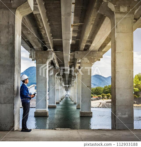 A male worker visually inspects concrete pier 112933188
