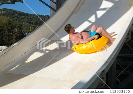 Overweight American tourist in amusement park on water slide 112933190