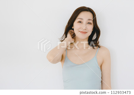 Young woman touching her hair in front of a white background 112933473