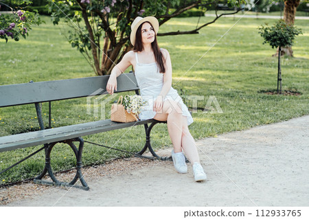 Relaxed Woman Sitting on Park Bench with Flowers Relaxed Woman Sitting on Park Bench with Flowers 112933765