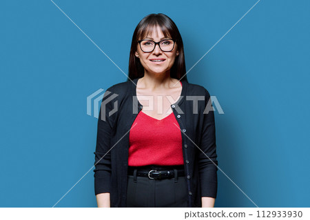 Smiling middle-aged woman on blue studio background Smiling middle-aged woman on blue studio background 112933930