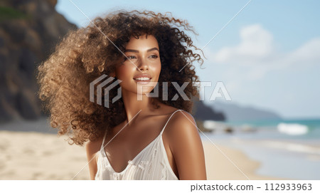 Radiant Young Woman with Curly Hair Enjoying Sunshine at Beach 112933963