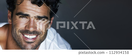Charismatic man with a warm smile, wearing a white shirt against a dark background. Charismatic man with a warm smile, wearing a white shirt against a dark background. 112934158