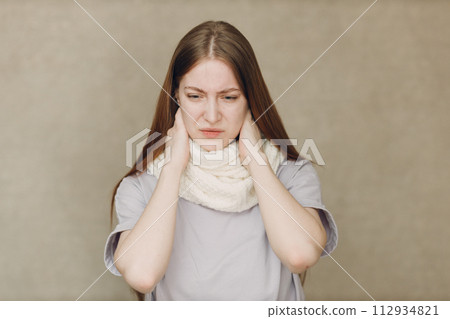 Young woman wearing scarf holds head flu catarrh ill sick disease treatment cold Young woman wearing scarf holds head flu catarrh ill sick disease treatment cold 112934821