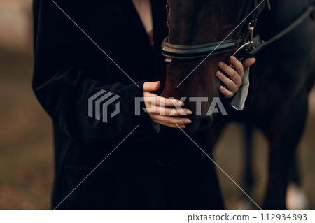 Female hands close up hold head her horse outdoors Female hands close up hold head her horse outdoors 112934893