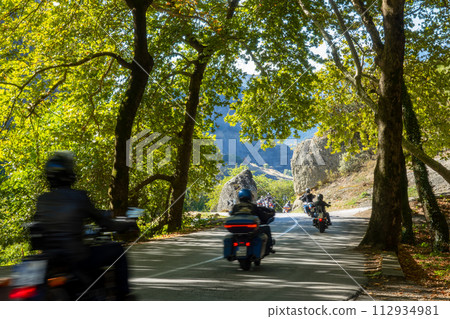 Group of Motorcyclists on a Forest Mountain Road 112934981