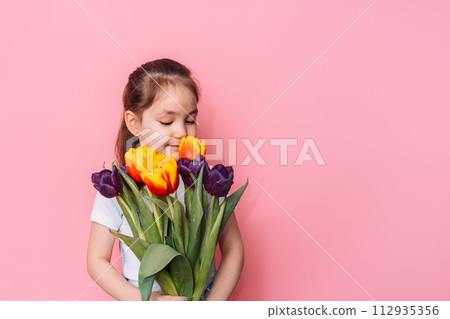 Child holding a bouquet of tulips in front of a pink background 112935356