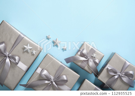 Set of monochrome gray gift boxes with gray ribbons and silver stars on light blue background. Copyspace Set of monochrome gray gift boxes with gray ribbons and silver stars on light blue background. Copyspace 112935525