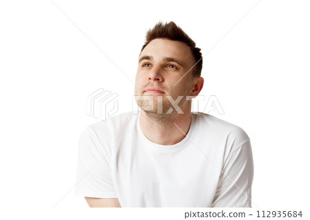Young dreaming man with short brunette hair looking up dressed white t-shirt against white studio background. 112935684
