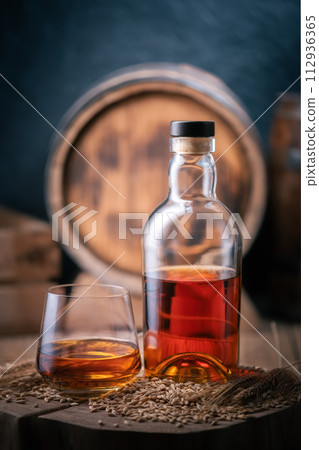 A glass of whiskey with bottle on wooden board A glass of whiskey with bottle on wooden board 112936365