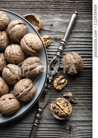 Walnut nuts and kernels in blue plate with a vintage silver nut cracker 112936404