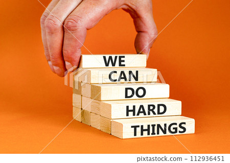 We can do hard things symbol. Concept words We can do hard things on wooden blocks. Beautiful orange table orange background. Businessman hand. Business, we can do hard things concept. Copy space. 112936451