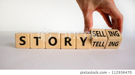 Storytelling or storyselling symbol. Businessman turns wooden cubes and changes the word 'storytelling' to 'storyselling'. Beautiful white background, copy space. Business and storytelling concept. 112936470