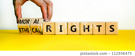 Ethical or moral rights symbol. Businessman turns wooden cubes and changes words ethical rights to moral rights on a beautiful white background. Business, ethical or moral rights concept. Copy space. 112936475