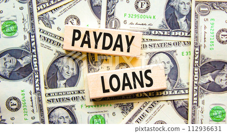 Payday loans symbol. Concept words Payday loans on beautiful wooden block. Beautiful background from dollar bills. Business and Payday loans concept. Copy space. 112936631