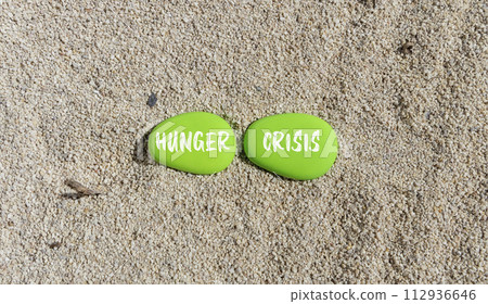 Hunger crisis symbol. Concept words Hunger crisis on beautiful green stone on a beautiful sand sea beach background. Business, support and Hunger crisis concept. Copy space. 112936646