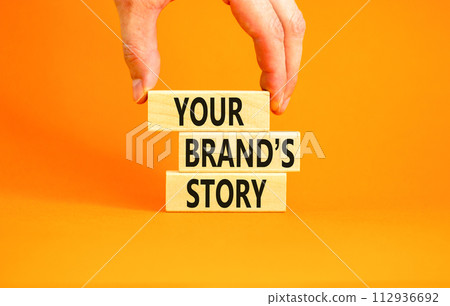 Branding and your brand story symbol. Concept words Your brands story on beautiful wooden blocks. Beautiful orange background. Businessman hand. Business branding your brand story concept. Copy space. 112936692