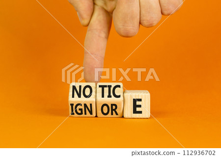 Notice or ignore symbol. Concept word Notice or Ignore on wooden cubes. Beautiful orange table orange background. Businessman hand. Business lifestyle and notice or ignore concept. Copy space. Notice or ignore symbol. Concept word Notice or Ignore on wooden cubes. Beautiful orange table orange background. Businessman hand. Business lifestyle and notice or ignore concept. Copy space. 112936702