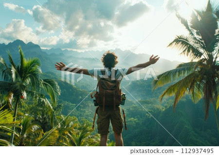 Tourist athlete rejoices climbing a mountain in a tropical country, success and goal achievement concept, man raised his hands up in delight 112937495
