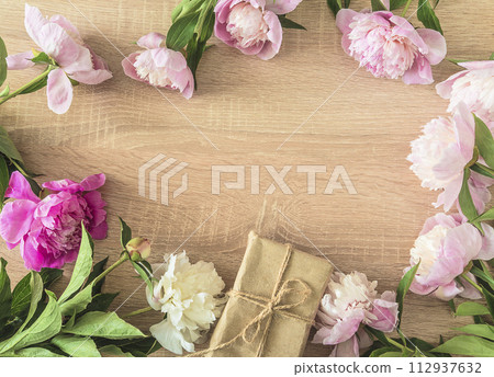 Happy mother's day greeting card template; frame of pink peonies flowers and craf gift box on a wooden background; copy space 112937632