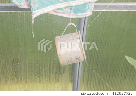 Old rusty tin mug hanging on a peg Old rusty tin mug hanging on a peg 112937723