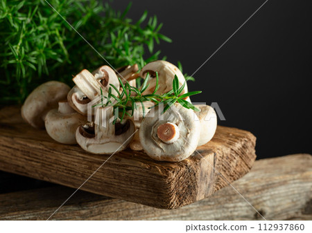 White champignons with rosemary on a wooden board. White champignons with rosemary on a wooden board. 112937860