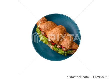 Delicious fresh crispy croissant with chicken or beef meat, lettuce, tomatoes, spices and sauce 112938058