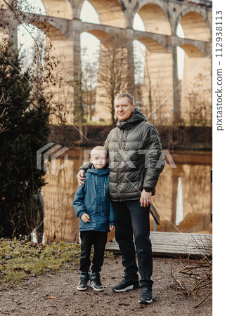 Family Serenity: Handsome 40-Year-Old Man and 8-Year-Old Son Amidst the Beauty of Neckar River and Historic Bridge, Bietigheim-Bissingen, Germany, Winter or Autumn 112938113