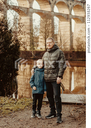Family Serenity: Handsome 40-Year-Old Man and 8-Year-Old Son Amidst the Beauty of Neckar River and Historic Bridge, Bietigheim-Bissingen, Germany, Winter or Autumn Family Serenity: Handsome 40-Year-Old Man and 8-Year-Old Son Amidst the Beauty of Neckar River and Historic Bridge, Bietigheim-Bissingen, Germany, Winter or Autumn 112938267