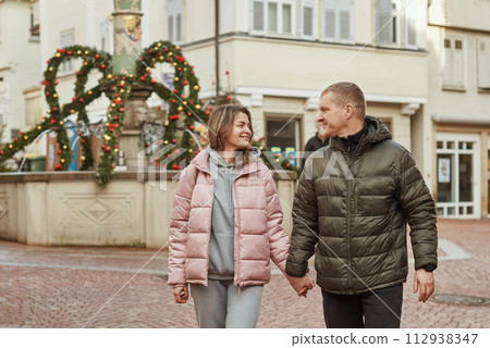 Loving couple of tourists walking around old town. Couple of lovers leisurely stroll in the cool autumn morning on the streets of a BIETIGHEIM-BISSINGEN (Germany). The guy holds his wife. Vacation 112938347
