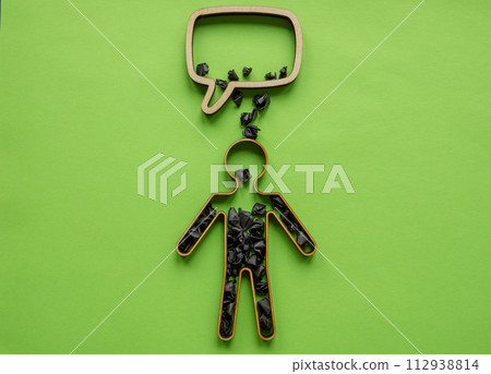 Speech bubble with negative comments and psychological abuse. Outline of a person with black paper balls. 112938814